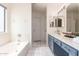 Bright bathroom featuring a soaking tub, white tile floors, and blue vanity at 13241 W Desert Ln, Surprise, AZ 85374