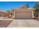 Exterior shot of a tan single-story home with a two-car garage and low-maintenance desert landscaping at 13241 W Desert Ln, Surprise, AZ 85374
