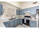 Lovely kitchen with blue cabinets, light counters, stainless steel sink, and modern appliances at 13241 W Desert Ln, Surprise, AZ 85374