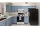 Updated kitchen with white counters, tile floors and blue cabinets with modern appliances and plenty of storage at 13241 W Desert Ln, Surprise, AZ 85374
