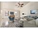 The staged living room with furniture, neutral walls, tile flooring, ceiling fan, and large windows creates a welcoming space at 13241 W Desert Ln, Surprise, AZ 85374