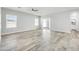 A bright living room featuring wood-look tile, multiple windows, a sliding door, and access to the kitchen at 14178 S Diablo Rd, Arizona City, AZ 85123