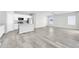 Open-concept living area with wood-look tile floors, white kitchen cabinets, stainless steel appliances, and a kitchen island at 14178 S Diablo Rd, Arizona City, AZ 85123