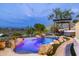 A backyard pool with rock features and a hot tub under a pergola create a backyard oasis at 15816 E Eagle Crest Rd, Fountain Hills, AZ 85268