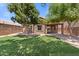 Spacious backyard featuring lush artificial turf, mature trees, and a covered patio at 15959 W Hearn Rd, Surprise, AZ 85379