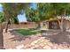 Well-maintained backyard with artificial grass, mature trees, and a stone-paved patio at 15959 W Hearn Rd, Surprise, AZ 85379