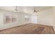 Bright living room with neutral carpet, multiple windows, and a contemporary ceiling fan at 1608 S 82Nd Dr, Phoenix, AZ 85043