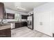 Modern kitchen with dark cabinets, stainless steel appliances, and laminate floors at 1733 N 77Th Dr, Phoenix, AZ 85035