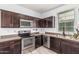 Kitchen with stainless steel appliances, dark cabinets and laminate flooring at 1733 N 77Th Dr, Phoenix, AZ 85035