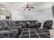 Spacious living room featuring a large grey sectional, wood flooring, and ceiling fan at 1733 N 77Th Dr, Phoenix, AZ 85035