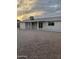 Rear view of a single-story home with a covered patio and low-maintenance gravel yard at dusk at 1813 E Boise St, Mesa, AZ 85203