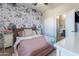 Stylish bedroom featuring a floral accent wall, a comfortable bed, and an ensuite bathroom, creating a cozy retreat at 20557 W Lost Creek Dr, Buckeye, AZ 85396