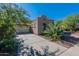 Attached two-car garage showcasing a wide driveway and mature landscaping under a clear blue sky at 20557 W Lost Creek Dr, Buckeye, AZ 85396