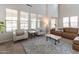 Open-concept living room with high ceilings, large windows, comfortable seating, and modern decor at 20557 W Lost Creek Dr, Buckeye, AZ 85396