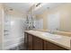 Well-lit bathroom with double sinks, a large mirror, and a shower-tub combination with a decorative curtain at 2111 N 77Th Gln, Phoenix, AZ 85035