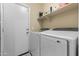 Modern laundry room featuring a side-by-side washer and dryer, as well as a utility door at 2111 N 77Th Gln, Phoenix, AZ 85035