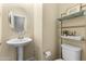 Bright powder room with a pedestal sink, toilet, and metal decorative shelves at 2111 N 77Th Gln, Phoenix, AZ 85035