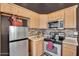 Compact kitchen featuring stainless steel appliances, light wood cabinets, and stylish backsplash at 2738 E Silversmith Trl, San Tan Valley, AZ 85143