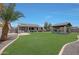 Wide shot of the lush green backyard featuring an outdoor kitchen and covered entertainment structure at 30308 W Whitton Ave, Buckeye, AZ 85396