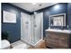 Stylish bathroom with dark blue walls, glass shower, a modern vanity, and elegant fixtures at 3224 E Desert Cove Ave, Phoenix, AZ 85028