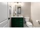 Bathroom vanity with a green cabinet, white countertop, gold hardware, toilet, and mirror at 3460 E Lynx Pl, Chandler, AZ 85249