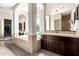 Primary bathroom with tub, dual vanities, stylish mirrors, and travertine stone at 3460 E Lynx Pl, Chandler, AZ 85249