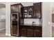 Kitchen area featuring a wine cooler, dark wood cabinets, granite counters, and stylish decor at 3460 E Lynx Pl, Chandler, AZ 85249