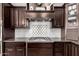 Close-up of a kitchen cooktop with dark cabinets, granite counters and white tile backsplash and decor details at 3460 E Lynx Pl, Chandler, AZ 85249