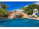 Beautiful backyard pool featuring a rock waterfall, slide, and lush landscaping for a relaxing retreat at 3460 E Lynx Pl, Chandler, AZ 85249