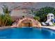 Stunning pool features a rock waterfall, slide, and lush tropical landscaping creating a backyard paradise at 3460 E Lynx Pl, Chandler, AZ 85249