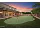 Beautiful backyard featuring a putting green, covered patio, lush greenery, and stone accents for outdoor entertainment at 3523 E Presidio Cir, Mesa, AZ 85213