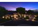 Twilight shot of the home's exterior featuring lush landscaping and a grand entrance with a circular driveway at 3523 E Presidio Cir, Mesa, AZ 85213