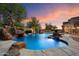 An inviting pool with a rock slide and lush landscaping provides a backyard oasis at 3523 E Presidio Cir, Mesa, AZ 85213