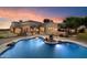 Custom pool with rock features and a view of the home's exterior under a beautiful dusk sky at 3523 E Presidio Cir, Mesa, AZ 85213