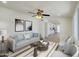 Living room with grey sofa, decorative pillows, wall art, ceiling fan, and view into the kitchen at 3650 E Laurel Ln, Phoenix, AZ 85028