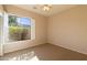 Sunlit bedroom featuring a large window, plantation shutters, and neutral carpet at 4241 E Andre Ave, Gilbert, AZ 85298