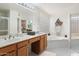 Bright bathroom with dual sinks, a soaking tub with glass blocks, and wood cabinetry at 4446 E Woodridge Dr, Phoenix, AZ 85032