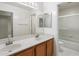 Bathroom featuring dual sinks, wood cabinets, mirror, and a tiled shower/tub combo at 4446 E Woodridge Dr, Phoenix, AZ 85032