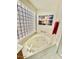 Bright bathroom featuring a large soaking tub, glass block window and tile floor at 4446 E Woodridge Dr, Phoenix, AZ 85032