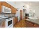 Open kitchen with white appliances, light wood cabinets, and wood floors, plus a view of fireplace at 4446 E Woodridge Dr, Phoenix, AZ 85032