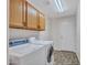 Well-equipped laundry room with washer, dryer, cabinets, shelving, and tile flooring at 11547 W King Snake Ct, Surprise, AZ 85378