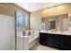 Bright bathroom featuring a double sink vanity, glass-enclosed shower, and a luxurious soaking tub at 13612 W Desert Moon Way, Peoria, AZ 85383
