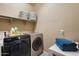 Functional laundry room featuring a front-load washer and dryer, storage baskets, and shelving at 13612 W Desert Moon Way, Peoria, AZ 85383