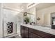 Clean and functional bathroom with a double sink vanity, mirrored cabinets, and a glass-enclosed shower at 17573 W Via De Luna Dr, Surprise, AZ 85387