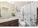 Bathroom featuring a single sink, dark cabinets, a toilet, and a shower with a decorative cactus-themed curtain at 17573 W Via De Luna Dr, Surprise, AZ 85387