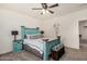 Comfortable main bedroom with a unique turquoise bed frame, ceiling fan, and warm carpeting at 17573 W Via De Luna Dr, Surprise, AZ 85387