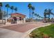A community entrance gate for Las Palmas featuring a guard house, gated entry and lush palm tree landscaping at 215 N Power Rd # 33, Mesa, AZ 85205