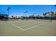 A tennis court with a green surface features a black net, light posts, and green shade structures at 215 N Power Rd # 33, Mesa, AZ 85205