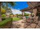 Relaxing backyard patio with shaded pergola, dining set, manicured lawn, and inviting pool area at 2308 E Aster Dr, Chandler, AZ 85286