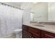Neutral bathroom featuring a patterned shower curtain and a vanity with warm colored cabinets and countertop at 2308 E Aster Dr, Chandler, AZ 85286